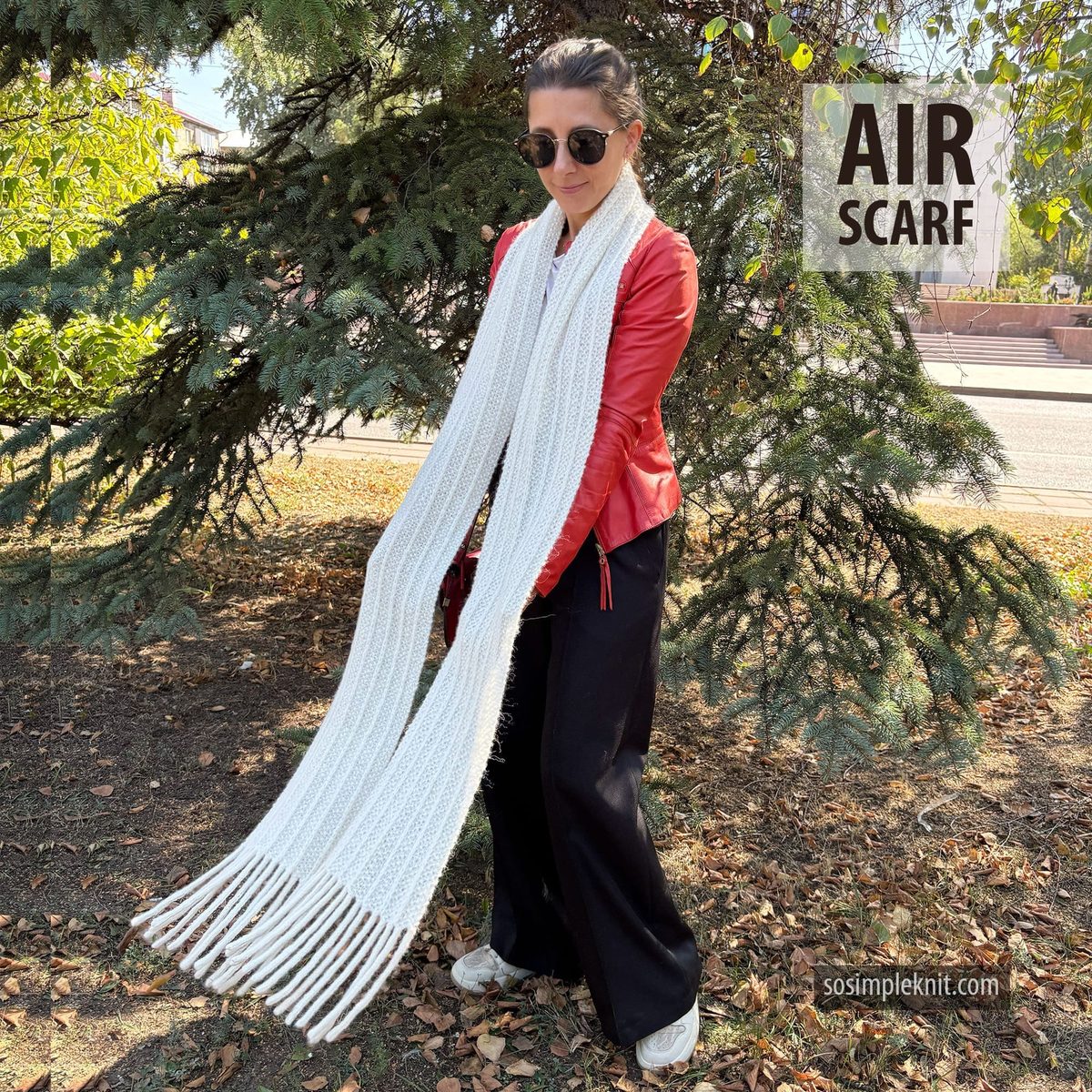 A person stands outdoors wearing a bright red leather jacket and sunglasses, holding a long, white scarf that drapes down to the ground. The background features green pine tree branches and a visible sidewalk, suggesting a casual setting. The scarf has a simple knitted texture with fringes at the ends. In the upper right corner, the text "AIR SCARF" is prominently displayed, along with a website URL.