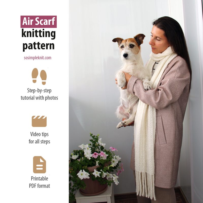 A woman wearing a long, light-colored scarf holds a small dog in her arms, standing beside a potted flowering plant. The setting is bright and minimalistic, with soft lighting illuminating the scene. The woman has long dark hair and is dressed in a casual outfit, while the dog is primarily white with brown spots. In the background, there is a plain wall that enhances the focus on the woman, dog, and plant. Text is displayed alongside the image, indicating it relates to a knitting pattern for the