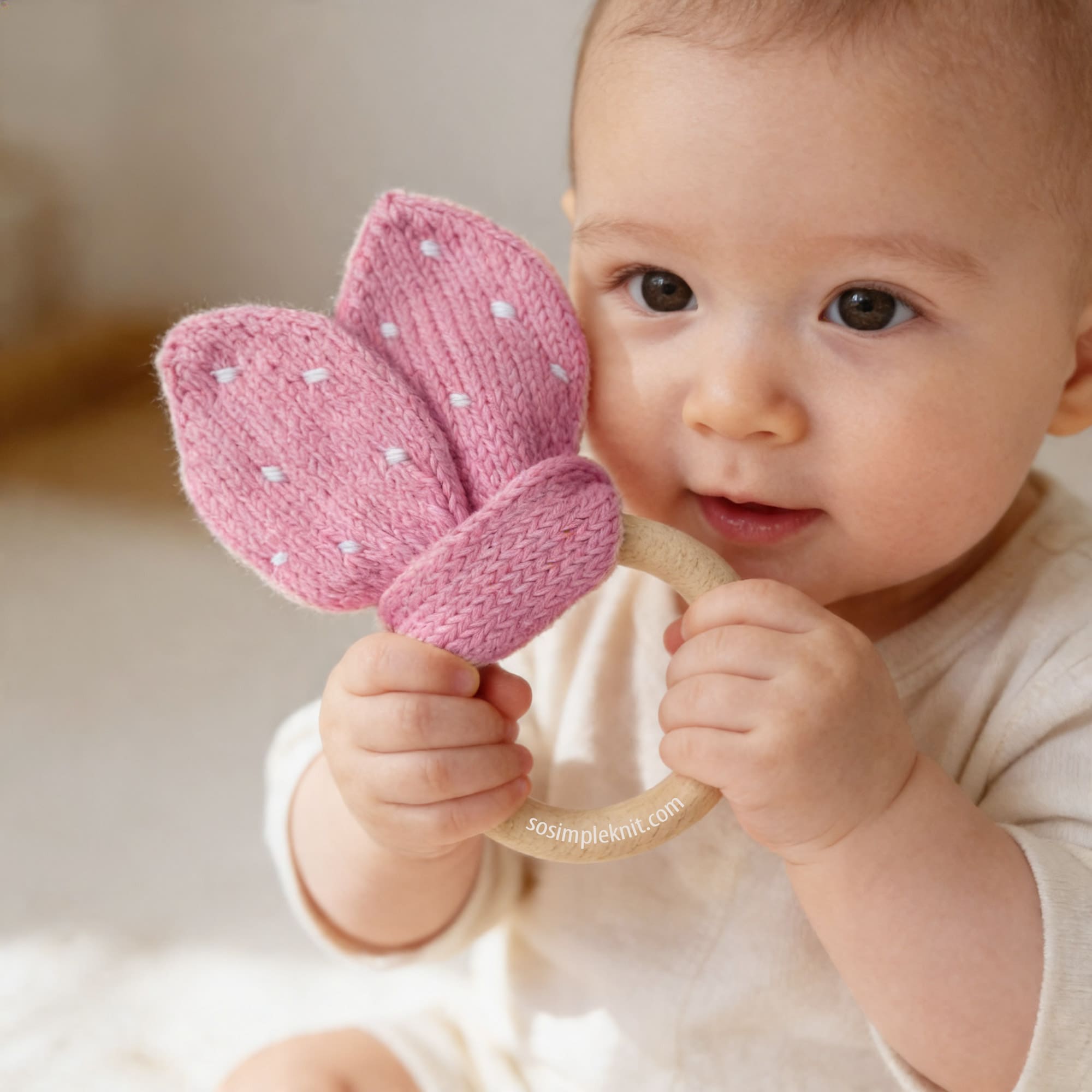 Pink bunny ears teething ring with wooden ring, handmade knitted baby toy on baby's hands