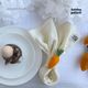 A beautifully decorated Easter table. It features a plate and a napkin held with a knitted carrot-shaped napkin ring.