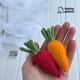 The photo shows a hand holding two colors of knitted carrots designed for decorating an Easter table. This is a knitting pattern for needle knitting