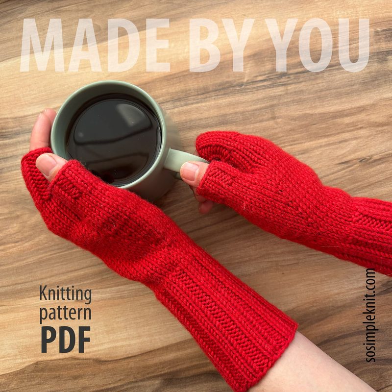 A pair of bright red fingerless gloves are worn by a person with light skin, who is holding a light green mug filled with dark liquid, likely coffee or tea. The gloves feature a ribbed texture and reach just above the wrist. The background consists of a warm wooden surface, providing a cozy feel to the image. Overlaid text in a bold font reads "MADE BY YOU" in the upper left corner, along with "Knitting pattern PDF" and the website "sosimpleknit.com" in the lower right corner.