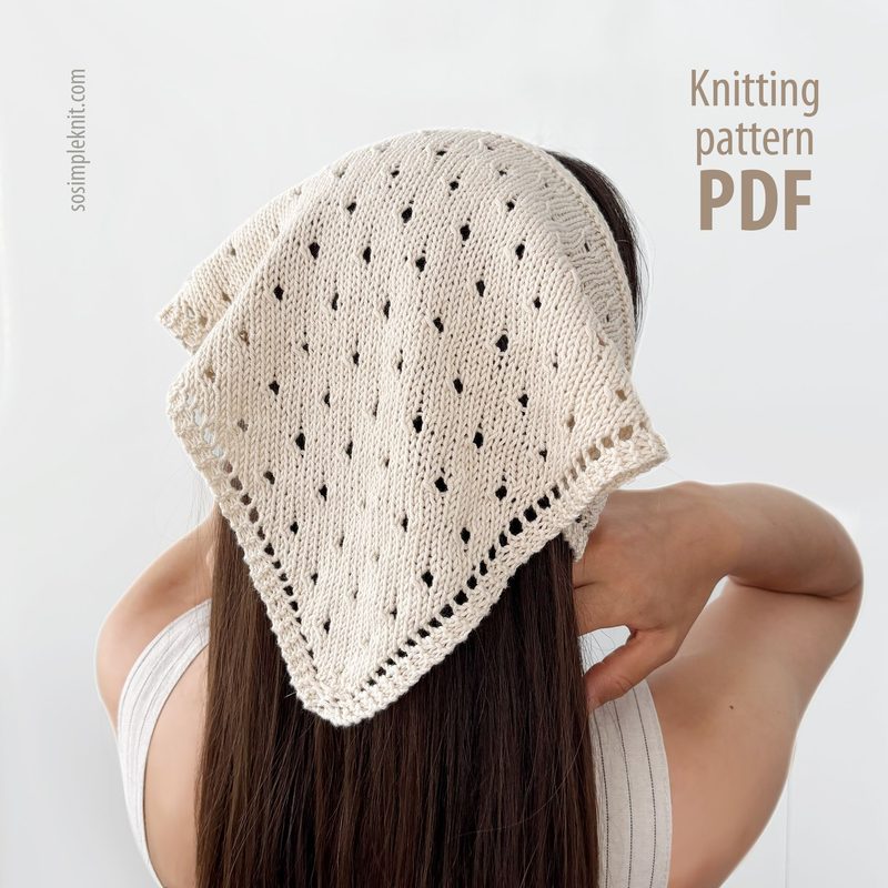 A woman with long brown hair is shown from behind, wearing a knitted triangular scarf positioned over her shoulders. The scarf is cream-colored with an intricate openwork pattern featuring small holes. The background is neutral, enhancing the focus on the scarf. Text on the right side reads "Knitting pattern PDF." The overall composition emphasizes the scarf's texture and design.