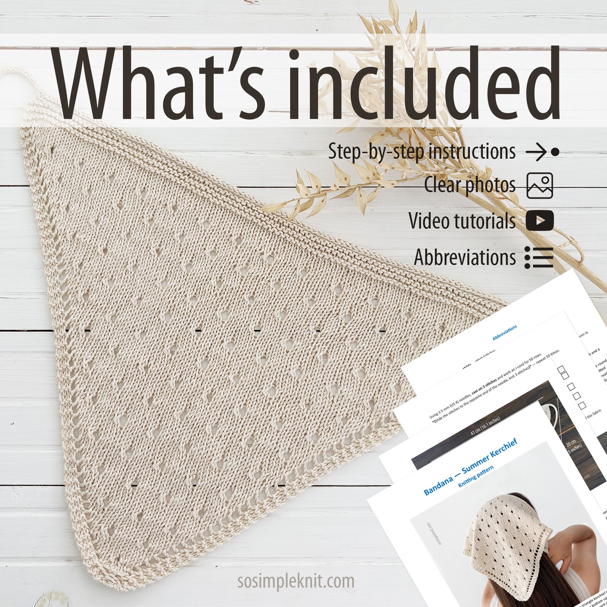 The image features a light beige knitted triangle scarf, draped elegantly on a light wooden surface. The scarf showcases an intricate openwork pattern, with small eyelet details throughout. In the background, there are printed instructional materials, including pages with clear photos and video tutorial icons, all arranged neatly alongside the scarf. The overall composition is well-lit and clean, emphasizing the texture and design of the scarf.