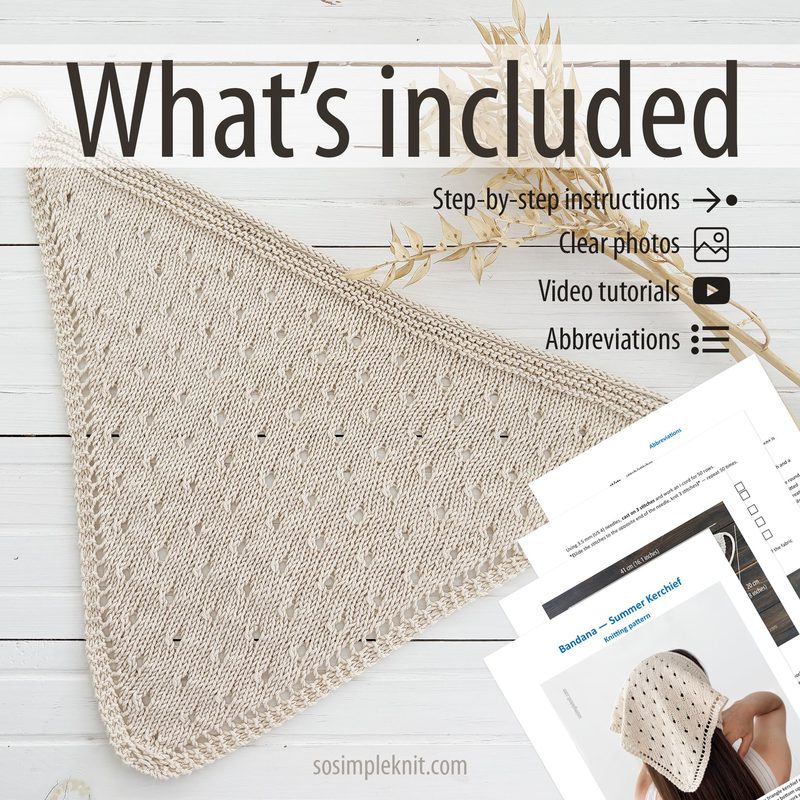 The image features a light beige knitted triangle scarf, draped elegantly on a light wooden surface. The scarf showcases an intricate openwork pattern, with small eyelet details throughout. In the background, there are printed instructional materials, including pages with clear photos and video tutorial icons, all arranged neatly alongside the scarf. The overall composition is well-lit and clean, emphasizing the texture and design of the scarf.