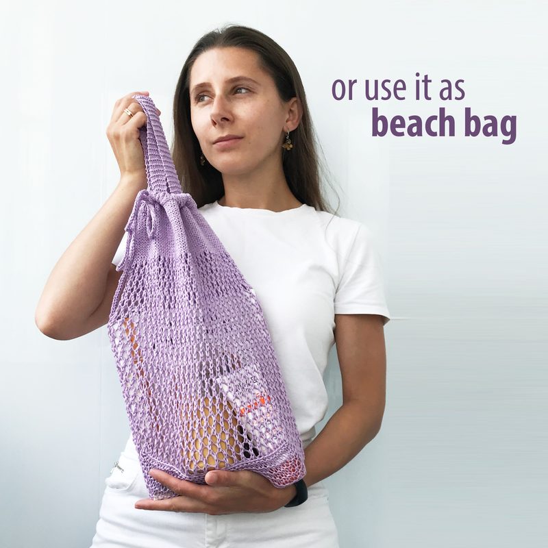 A woman with long brown hair is holding a lavender knitted produce bag filled with items, standing against a light gray background. She is wearing a plain white t-shirt and appears thoughtful, gazing slightly to the side. The text "or use it as beach bag" is displayed in purple next to her. The bag has a loose, net-like structure, emphasizing its versatility.