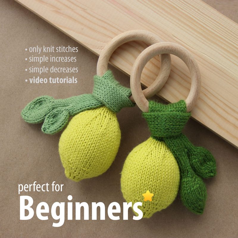 The image features two knitted lemon-shaped items with green leaves, attached to wooden rings. The lemons are bright yellow with textured knitting patterns, and the leaves are a vibrant green. The background consists of a light wooden surface, and there is a text overlay in white and yellow that reads "perfect for Beginners" along with bullet points mentioning "only knit stitches," "simple increases," "simple decreases," and "video tutorials." The overall color palette is warm and inviting.