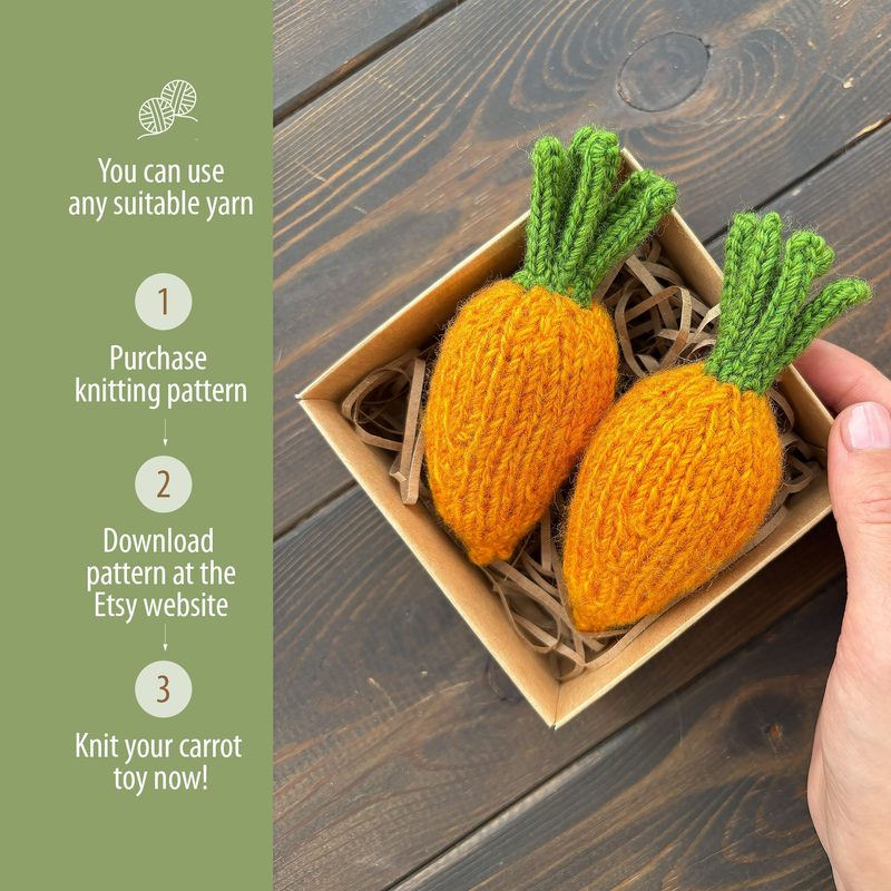 The image shows two small knitted carrots resting in a brown cardboard box filled with straw-like filler. The carrots are bright orange with textured body and vibrant green knitted tops. To the left of the box, there is a hand holding it, and there are three instructional steps in white text on the left side of the image, each numbered. The background features a wooden surface in warm brown hues, creating a natural and cozy ambiance.