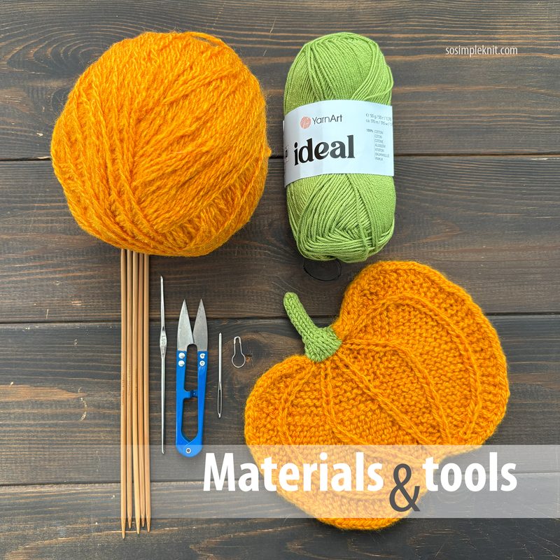 The image displays a vibrant orange ball of yarn next to a green skein, with a completed knitted pumpkin motif placed next to them. Above, a pair of knitting needles and a small pair of scissors are positioned alongside a stitch marker and a blue crochet hook. The background consists of a dark wooden surface, with the text "Materials & tools" prominently displayed at the bottom in white and gray.