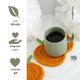 A cozy scene featuring a light green mug filled with black coffee, placed on a vibrant orange knitted pumpkin coaster. The coaster is circular and textured, resembling a pumpkin's shape and color. In the background, soft white fabric flowers add a touch of contrast. To the left, there are graphic icons representing fall crafts, scrap yarn projects, and handmade gifts, each accompanied by corresponding text in a minimalist style. The overall composition creates a warm and inviting atmosphere, emp