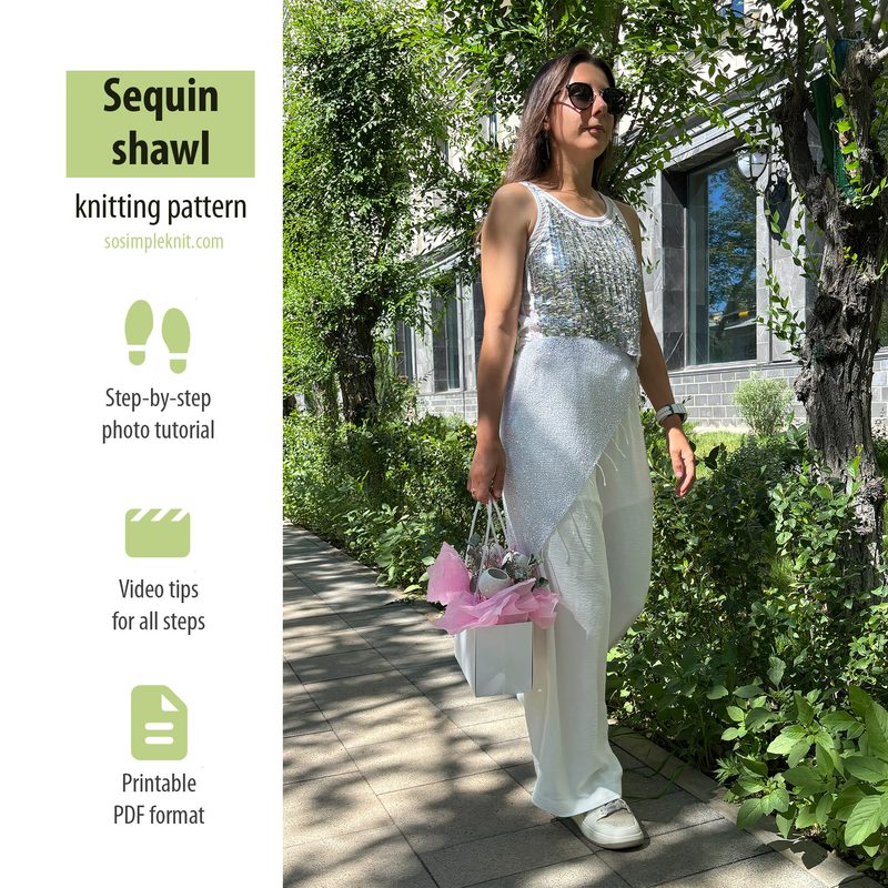 A woman is walking outdoors along a stone pathway bordered by greenery, wearing a white sleeveless top adorned with sequins. She has on loose white trousers and is carrying a white handbag with pink accents. The background features trees and a modern building, while natural sunlight casts shadows on the ground. Text on the left side includes the title "Sequin shawl knitting pattern" along with details about a tutorial, video tips, and a printable PDF format.