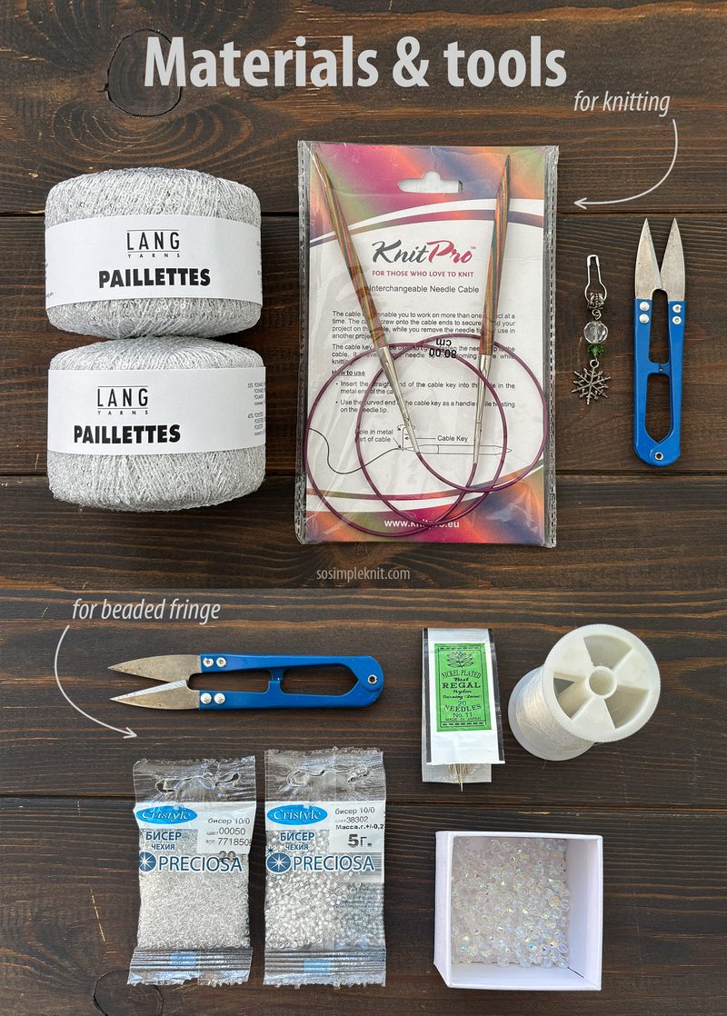 The image shows a flat lay of knitting materials and tools arranged on a dark wood surface. There are two skeins of yarn labeled "LANG PAILLETTES" in a light silver color. A set of knitting needles is enclosed in a plastic package, accompanied by a charm and small scissors. To the right, there is a small spool of thread and various packets of beads labeled "PRECIOSA." A cardboard box is placed in the bottom right corner.