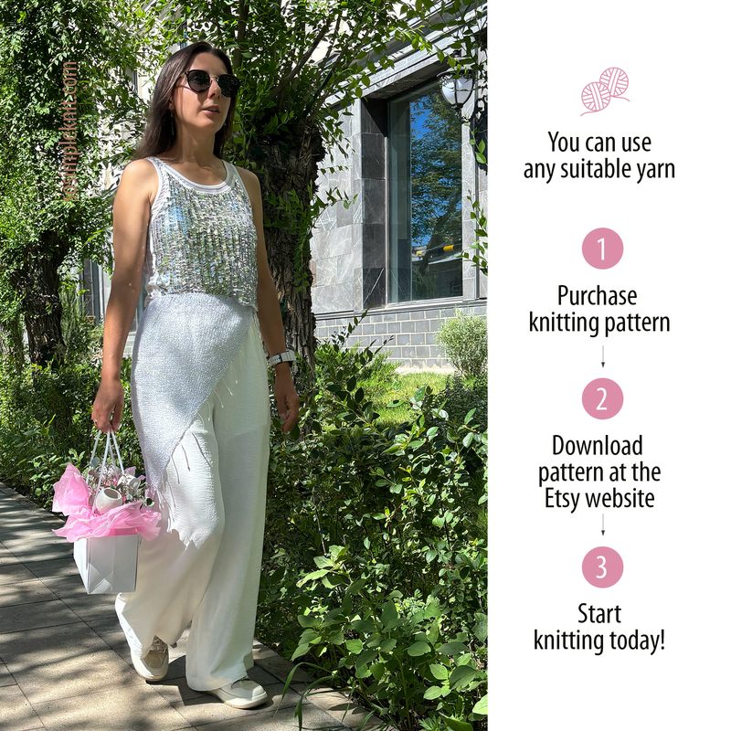 A woman walks along a paved path, wearing a sleeveless white top adorned with silver sequins that shimmer in the sunlight, paired with white pants. She carries a white handbag with pink accents. The background features leafy green trees and a grey stone building, with bright sunlight filtering through the leaves, creating a lively outdoor scene. The composition is framed by foliage, giving a natural and vibrant atmosphere.