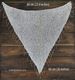 A triangular sequin shawl is displayed against a dark wooden background. The shawl is primarily white, embellished with shiny silver sequins that reflect light. The edges are finished with loose, delicate threads that hang down slightly. Measurement lines indicate the dimensions of the shawl, with the width marking 60 cm (23.6 inches) and the height marking 66 cm (26 inches). The overall composition is focused on showcasing the shawl's design and texture.