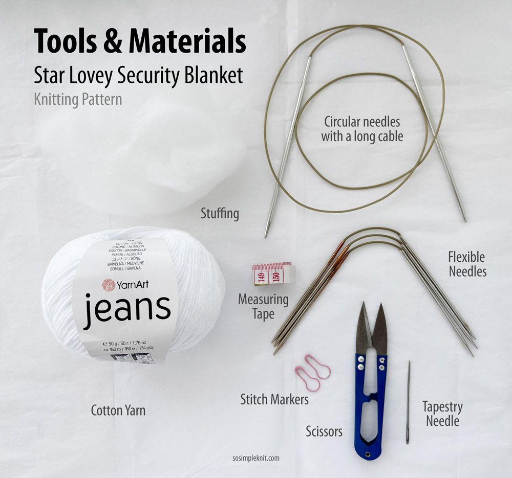 The image shows a flat lay of materials for the "Star Lovey Security Blanket" knitting pattern on a light background. It includes a ball of white cotton yarn labeled "YarnArt jeans," a long circular knitting needle, stuffing, flexible needles, scissors, a measuring tape, stitch markers, a tapestry needle, and some paper clips. The items are arranged neatly, with labels placed at the top indicating "Tools & Materials." The overall color palette is predominantly white with hints of pastel.