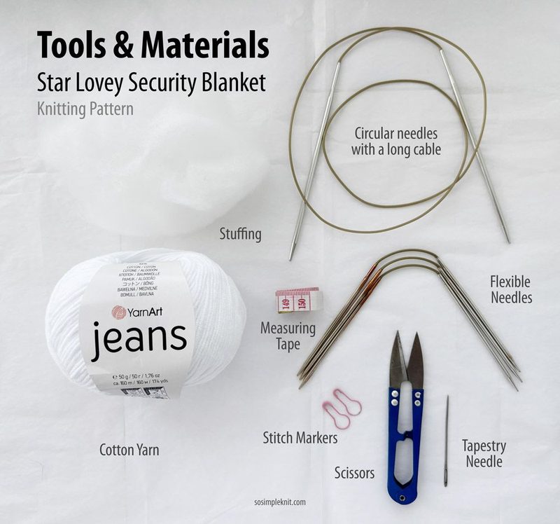 The image shows a flat lay of materials for the "Star Lovey Security Blanket" knitting pattern on a light background. It includes a ball of white cotton yarn labeled "YarnArt jeans," a long circular knitting needle, stuffing, flexible needles, scissors, a measuring tape, stitch markers, a tapestry needle, and some paper clips. The items are arranged neatly, with labels placed at the top indicating "Tools & Materials." The overall color palette is predominantly white with hints of pastel.