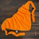 A vibrant orange lace triangle scarf is laid out on a dark wooden surface. The scarf features a delicate, airy texture, showcasing small holes throughout its fabric. It is styled with a cowl neck and has two long ties extending from the edges, creating a relaxed drape. The overall look is soft and inviting, emphasizing the intricate knitting pattern.